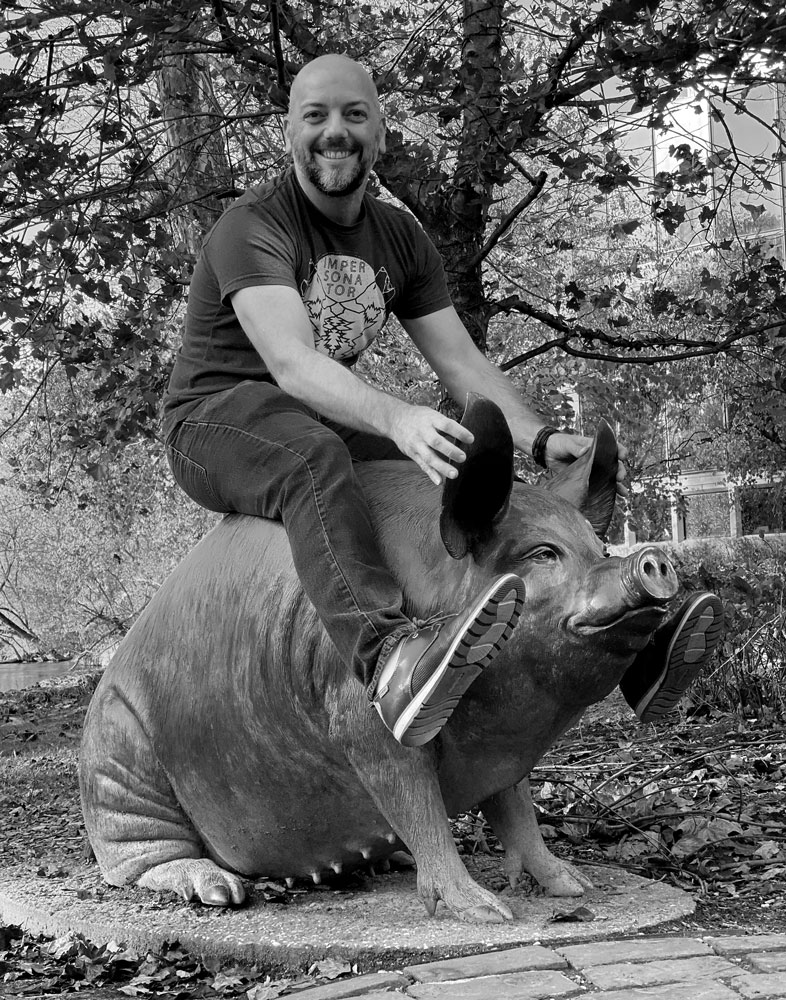 Image shows fantasy artist Jeff Miracola riding a bronze pig at the Brandywine Museum in Pennsylvania.